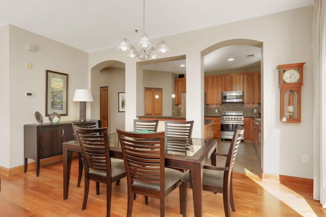 dining space with light hardwood / wood-style floors and a notable chandelier