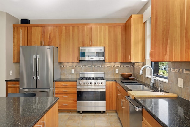 kitchen featuring backsplash, sink, dark stone counters, and premium appliances