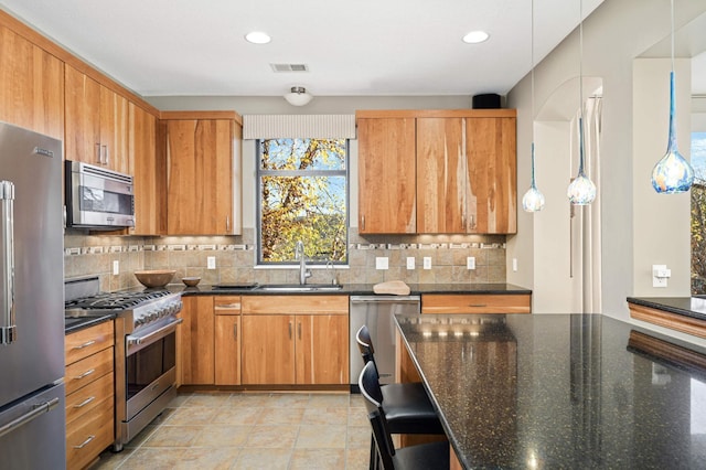 kitchen featuring premium appliances, decorative backsplash, and dark stone counters