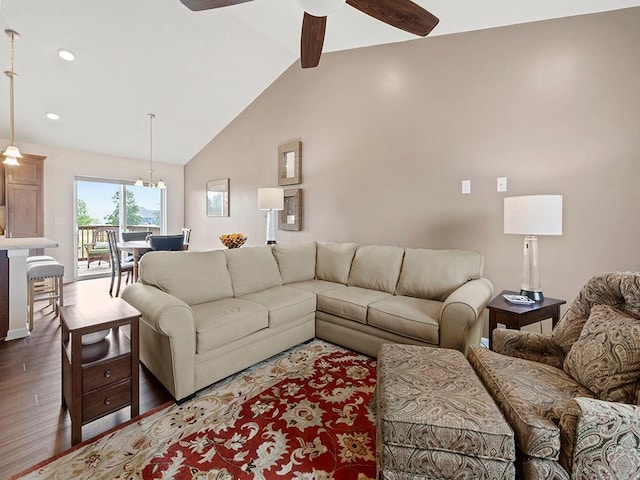 living room with ceiling fan with notable chandelier, high vaulted ceiling, and dark hardwood / wood-style flooring