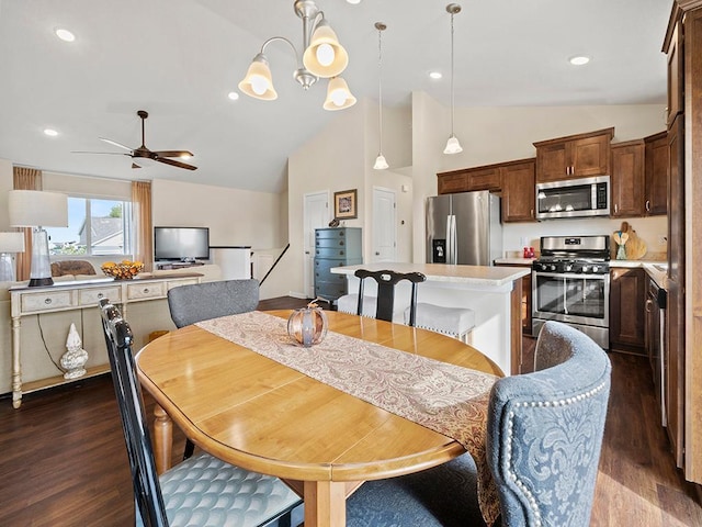 dining room with ceiling fan with notable chandelier, dark wood-type flooring, and vaulted ceiling