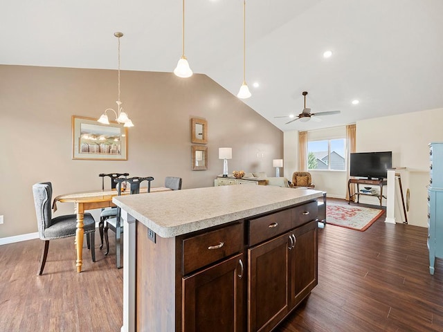 kitchen featuring hanging light fixtures, ceiling fan with notable chandelier, dark hardwood / wood-style floors, and a center island