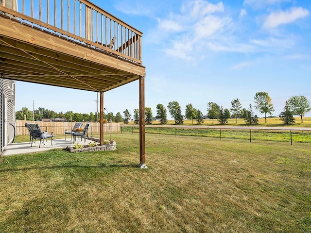 view of yard featuring a rural view, a wooden deck, and a patio area