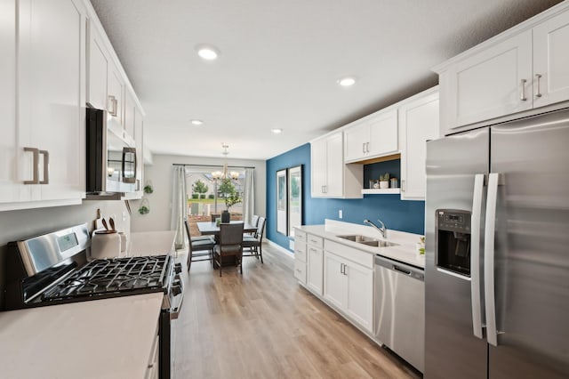 kitchen with hanging light fixtures, stainless steel appliances, white cabinetry, and sink