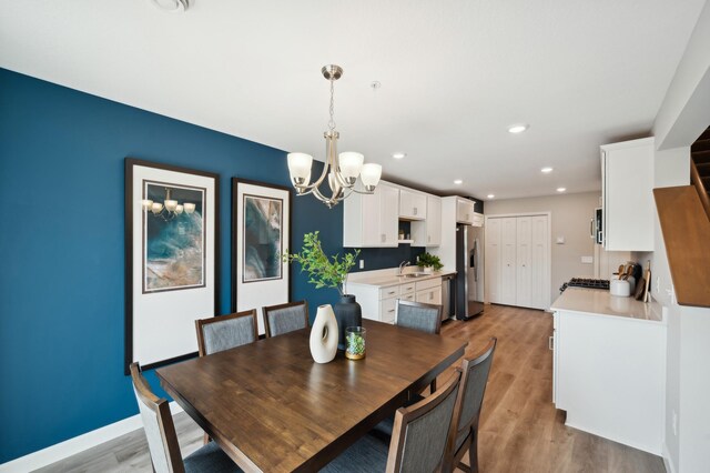 dining space with an inviting chandelier, sink, and light hardwood / wood-style floors