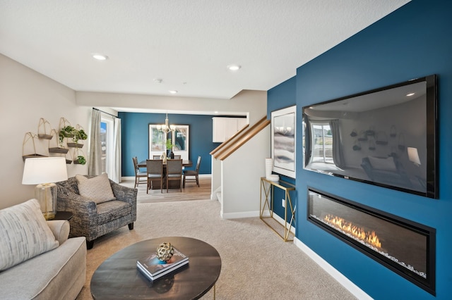 living room with light carpet, a textured ceiling, and a notable chandelier