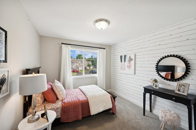 carpeted bedroom featuring a textured ceiling and wooden walls