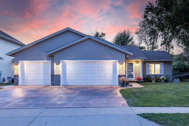 ranch-style house featuring a garage and a lawn