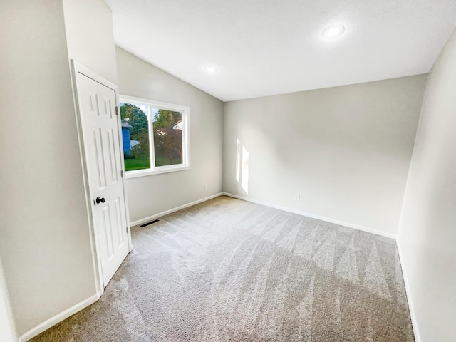 carpeted spare room with lofted ceiling