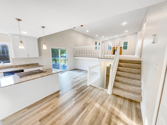 kitchen featuring light hardwood / wood-style flooring, dishwasher, white cabinetry, hanging light fixtures, and lofted ceiling