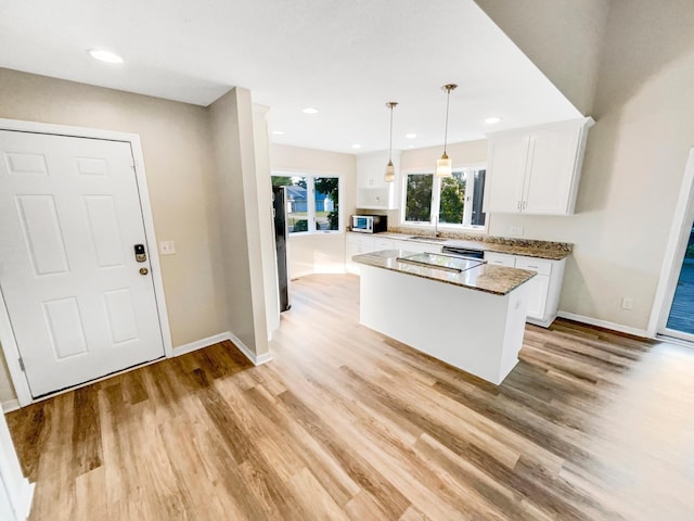 kitchen with light wood-type flooring, white cabinetry, hanging light fixtures, and a kitchen island