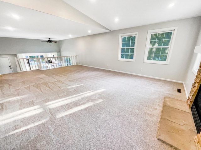 interior space featuring a wealth of natural light, ceiling fan, carpet, and vaulted ceiling