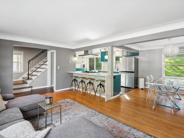 living room with a notable chandelier, ornamental molding, and hardwood / wood-style flooring