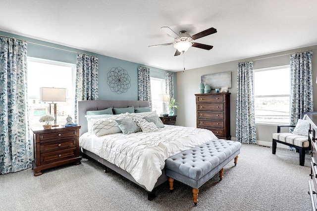 bedroom featuring ceiling fan, light colored carpet, and multiple windows