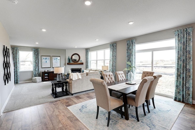 dining space featuring a textured ceiling, light wood-type flooring, and a large fireplace