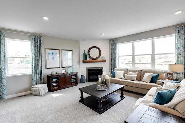 living room featuring carpet floors, a textured ceiling, and a fireplace