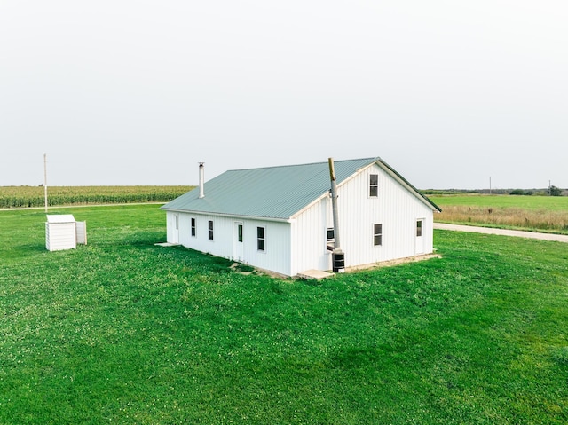 view of property exterior featuring a rural view, a lawn, and central air condition unit