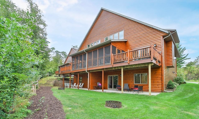 rear view of house featuring a sunroom, a patio area, a deck, a lawn, and an outdoor fire pit