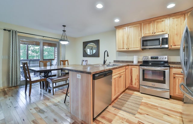 kitchen featuring pendant lighting, sink, kitchen peninsula, light hardwood / wood-style flooring, and stainless steel appliances