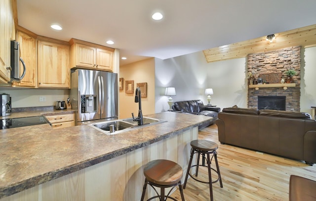 kitchen featuring sink, a kitchen bar, light hardwood / wood-style flooring, stainless steel appliances, and light brown cabinetry