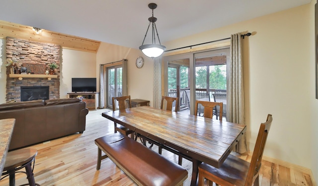 dining area with light wood-type flooring, a fireplace, and beam ceiling