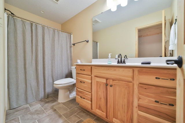 bathroom with walk in shower, vanity, and toilet