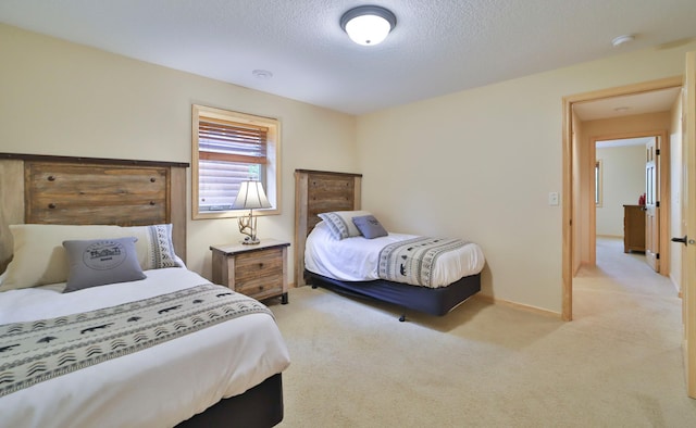 bedroom with light colored carpet and a textured ceiling