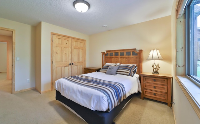 carpeted bedroom with a textured ceiling and a closet