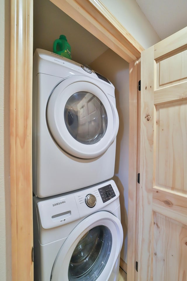 clothes washing area with stacked washing maching and dryer