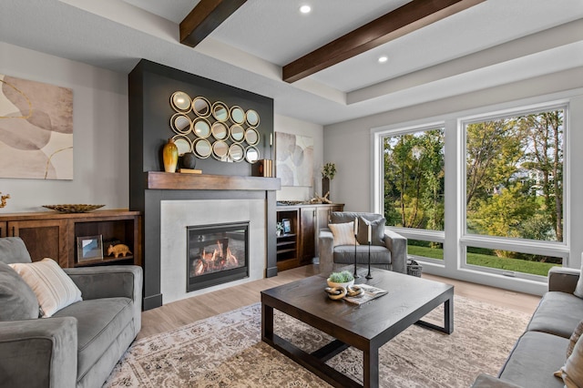 living room featuring a fireplace, beamed ceiling, and light hardwood / wood-style floors