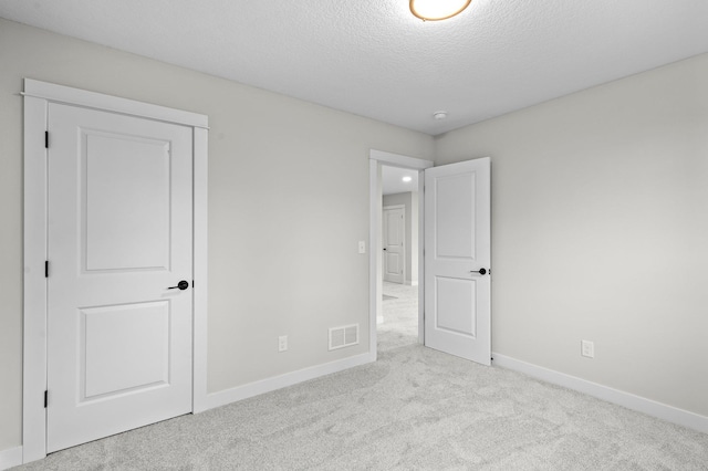 unfurnished bedroom featuring a textured ceiling and light carpet