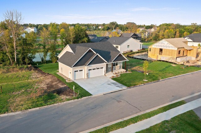 view of front facade with a shingled roof, concrete driveway, a residential view, board and batten siding, and a front yard