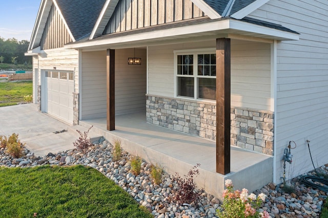 property entrance with a porch, a shingled roof, board and batten siding, a garage, and stone siding