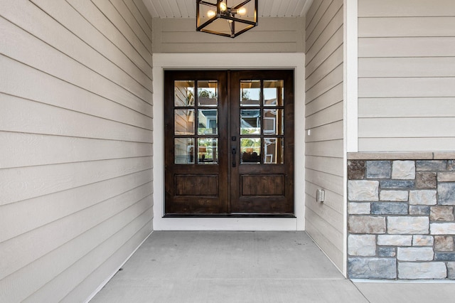 view of exterior entry featuring stone siding and french doors