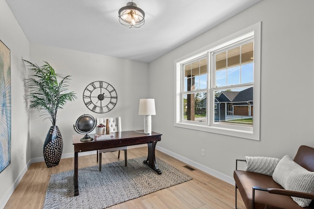 office with light wood finished floors, visible vents, and baseboards