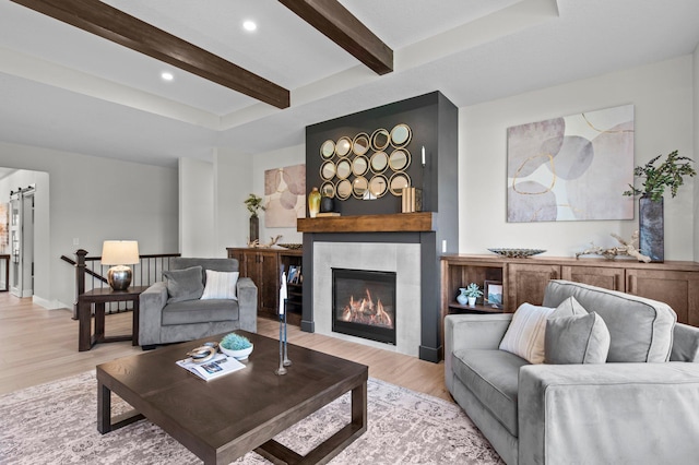 living area with recessed lighting, a fireplace, beamed ceiling, and light wood-style flooring