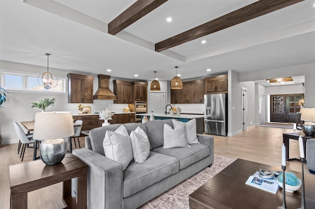 living room featuring a chandelier, light wood-style flooring, recessed lighting, baseboards, and beam ceiling