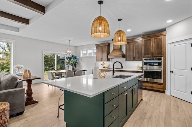 kitchen featuring light wood-style floors, double oven, light countertops, and a sink