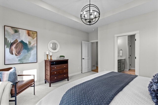 bedroom featuring a tray ceiling, an inviting chandelier, light carpet, connected bathroom, and baseboards