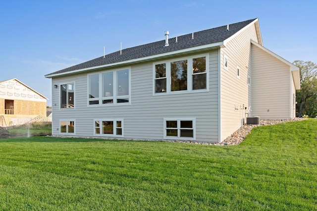 rear view of property with a yard and a shingled roof