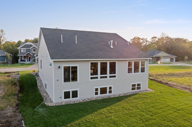 rear view of house with a shingled roof and a lawn