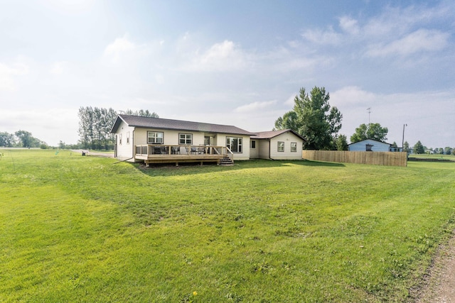 rear view of house with a lawn, fence, and a wooden deck