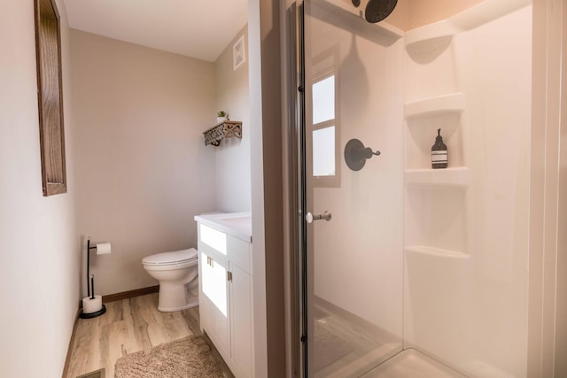 full bathroom featuring a shower stall, baseboards, toilet, wood finished floors, and vanity