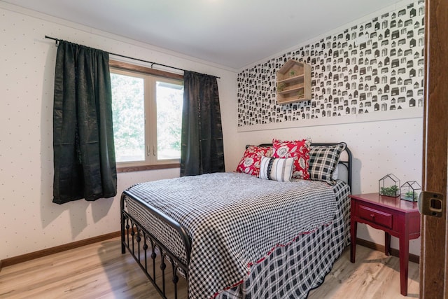 bedroom featuring wallpapered walls, baseboards, and light wood finished floors