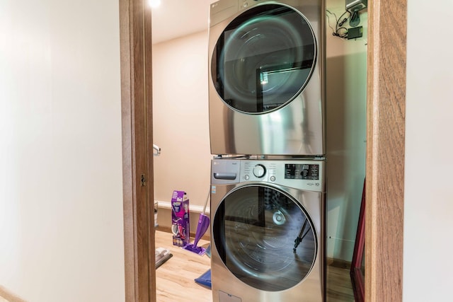 laundry room with stacked washer / dryer, laundry area, and wood finished floors