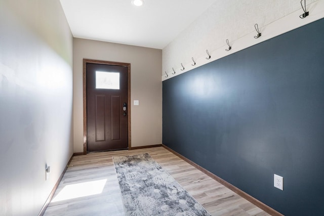 doorway to outside featuring baseboards and light wood-style flooring