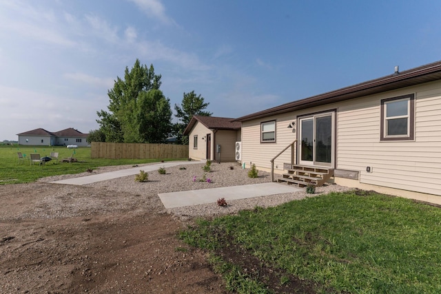 back of property featuring a patio area, a lawn, entry steps, and fence