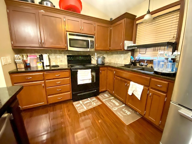 kitchen with backsplash, hanging light fixtures, dark wood-type flooring, stainless steel appliances, and sink