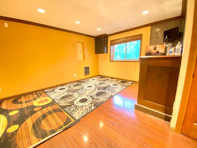 living room with wood-type flooring, heating unit, and crown molding