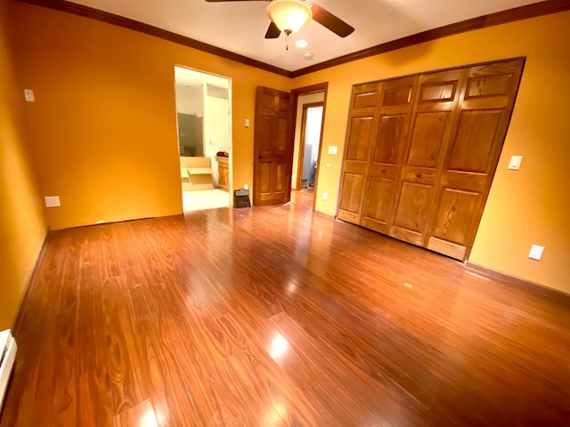 unfurnished bedroom featuring light hardwood / wood-style flooring, a closet, crown molding, a baseboard heating unit, and ceiling fan